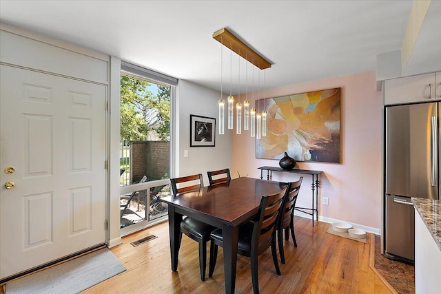 dining space with visible vents, baseboards, and light wood-style floors