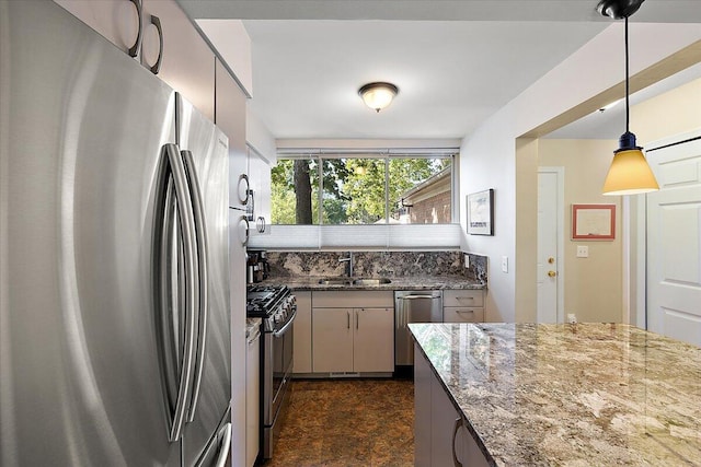 kitchen featuring a sink, hanging light fixtures, appliances with stainless steel finishes, and dark stone countertops