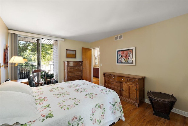 bedroom featuring access to exterior, wood finished floors, baseboards, and visible vents
