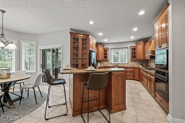 1171 Deer Path Trl, Oxford, MI 48371 - kitchen featuring black appliances, brown cabinetry, a breakfast bar area, light stone countertops, and tasteful backsplash