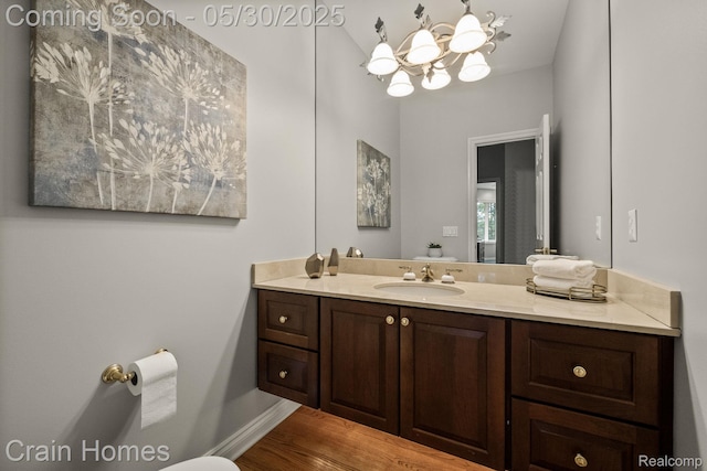 1171 Deer Path Trl, Oxford, MI 48371 - bathroom featuring vanity, a chandelier, wood finished floors, toilet, and baseboards