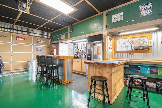 bar featuring a community bar, finished concrete floors, and stainless steel fridge