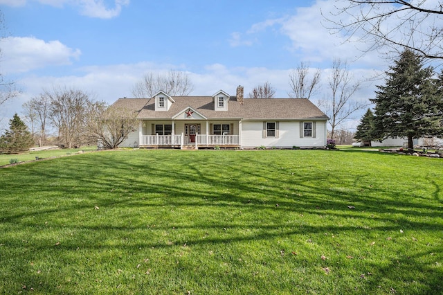 new england style home featuring a front yard, a chimney, and a porch