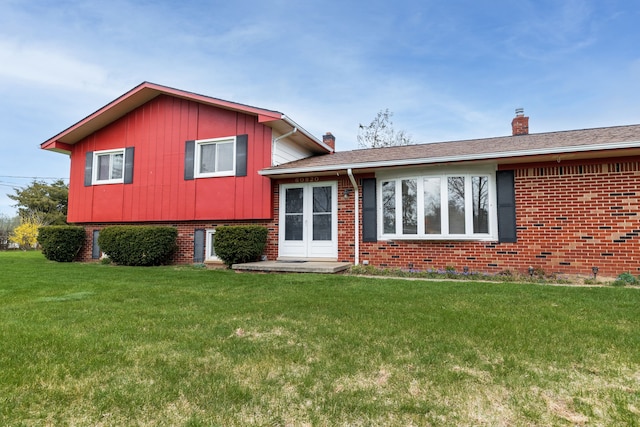 view of front of house featuring a chimney, a front yard, and brick siding