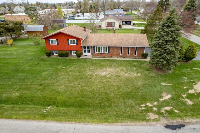 rear view of property featuring a residential view, roof with shingles, a yard, and brick siding