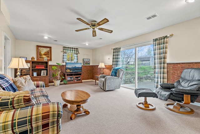 living room featuring visible vents, a ceiling fan, a wainscoted wall, and carpet