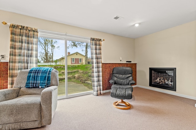sitting room featuring baseboards, carpet floors, and a glass covered fireplace