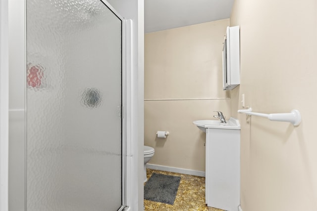 bathroom with toilet, a stall shower, vanity, and baseboards