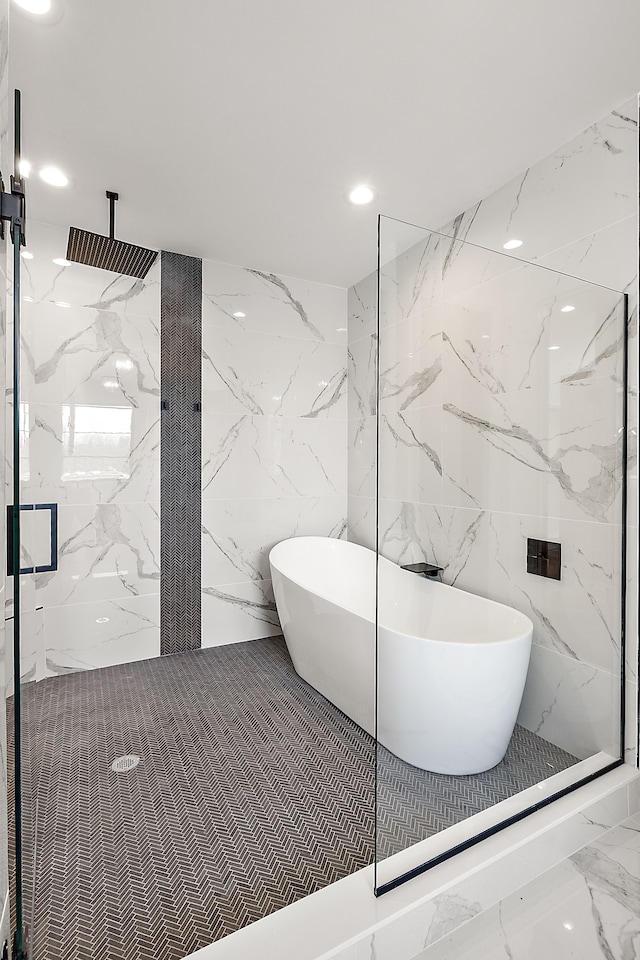 bathroom with recessed lighting, tile walls, a freestanding tub, and a marble finish shower