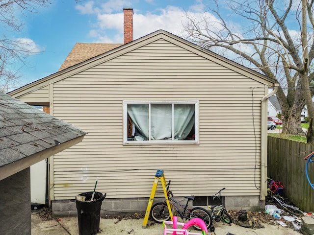 19965 Barlow St, Detroit, MI 48205 - view of side of home with a chimney, a shingled roof, and fence
