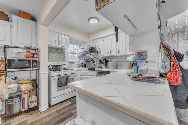 19965 Barlow St, Detroit, MI 48205 - kitchen featuring tasteful backsplash, white cabinets, white range with gas cooktop, wood finished floors, and tile countertops