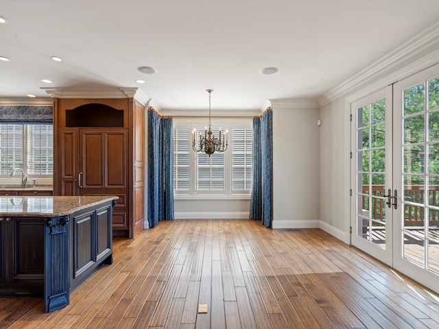 kitchen with an inviting chandelier, light wood-style flooring, a sink, baseboards, and french doors
