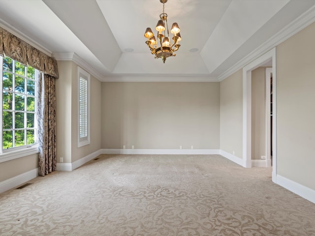 carpeted empty room featuring a chandelier, baseboards, a raised ceiling, and ornamental molding