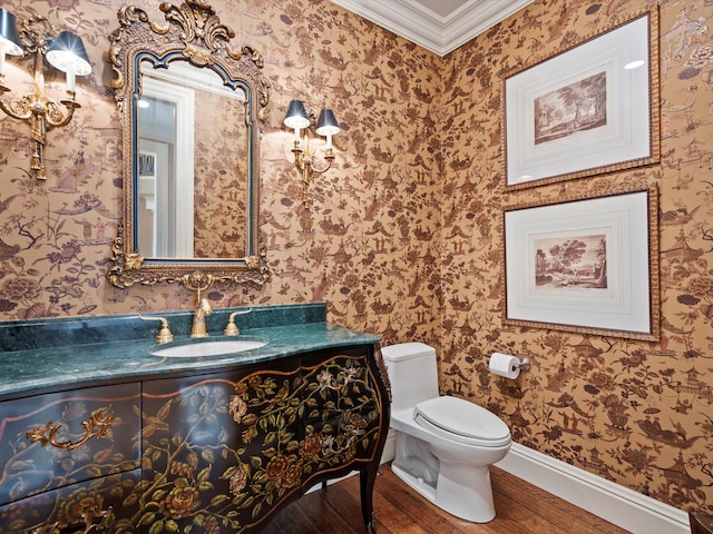 half bathroom featuring crown molding, wallpapered walls, wood finished floors, and baseboards