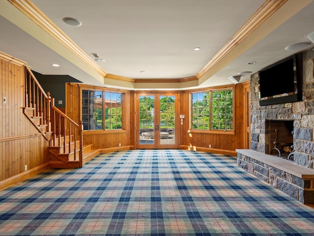 unfurnished living room with a stone fireplace, stairway, carpet, and baseboards