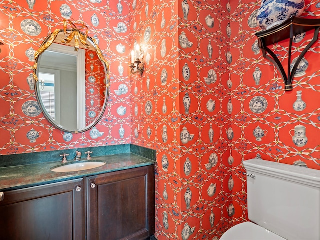 bathroom with wallpapered walls, toilet, and vanity