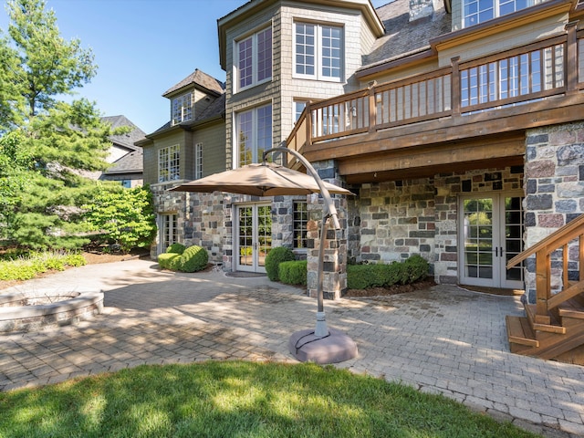 rear view of house with stone siding, french doors, and a patio area