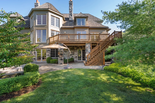 back of property with a chimney, a deck, stairway, french doors, and a lawn