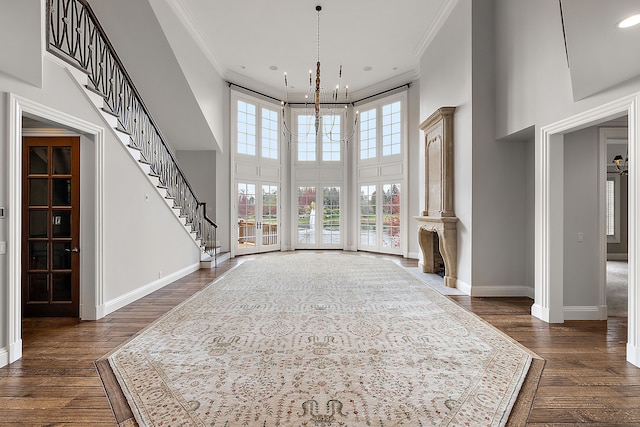 foyer with baseboards, ornamental molding, an inviting chandelier, and dark wood finished floors