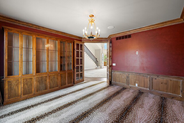unfurnished dining area with an inviting chandelier, stairway, ornamental molding, carpet flooring, and visible vents
