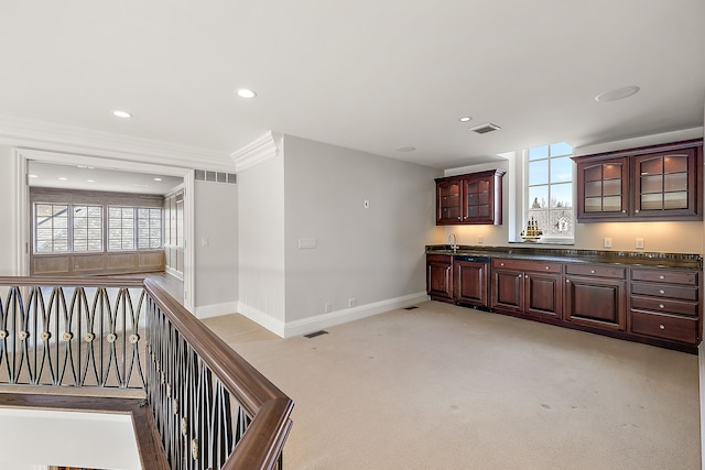 kitchen with glass insert cabinets, light carpet, dark countertops, baseboards, and visible vents