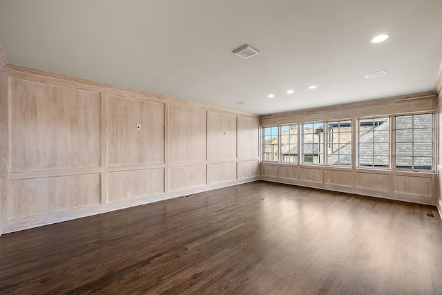 unfurnished room with visible vents, recessed lighting, dark wood-style flooring, and a decorative wall