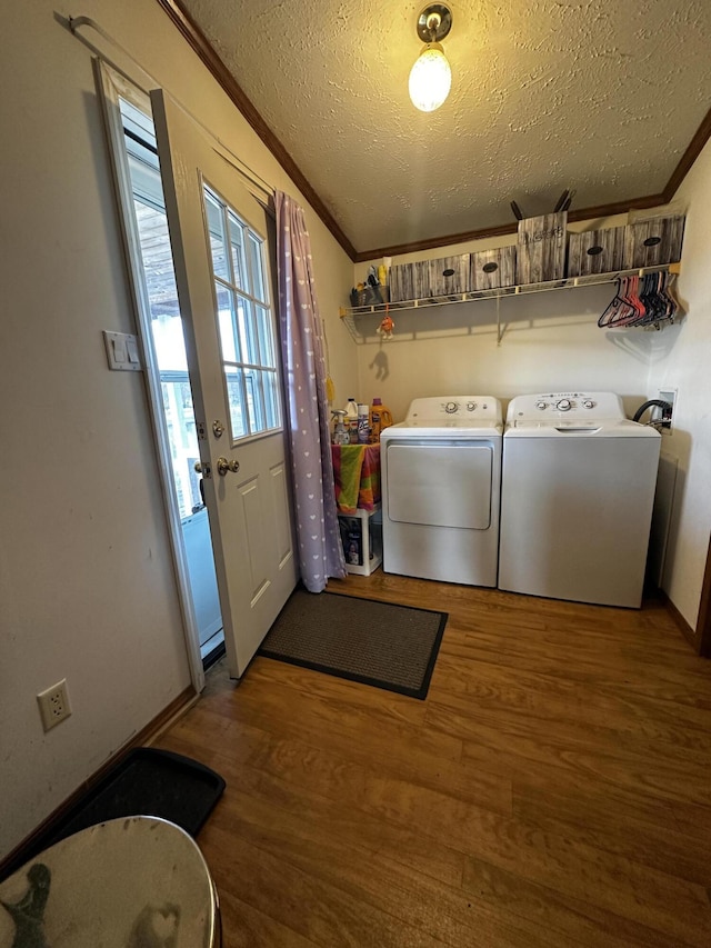 clothes washing area featuring wood finished floors, laundry area, washing machine and clothes dryer, crown molding, and a textured ceiling