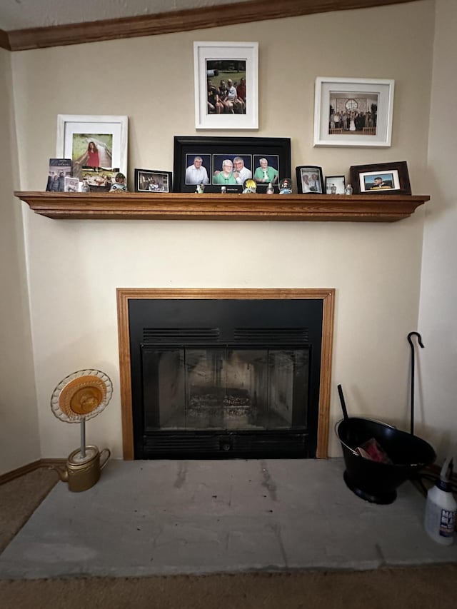 details featuring crown molding, carpet flooring, baseboards, and a glass covered fireplace