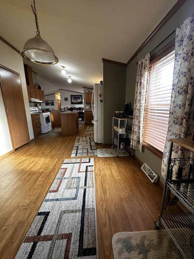 living area featuring light wood finished floors, ornamental molding, lofted ceiling, and a textured ceiling