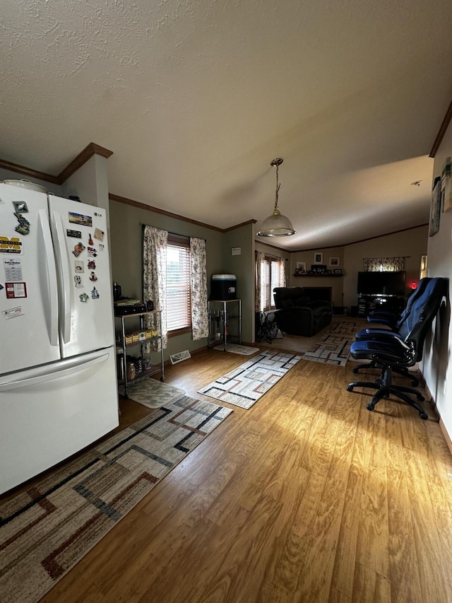 living area with baseboards, visible vents, crown molding, and wood finished floors