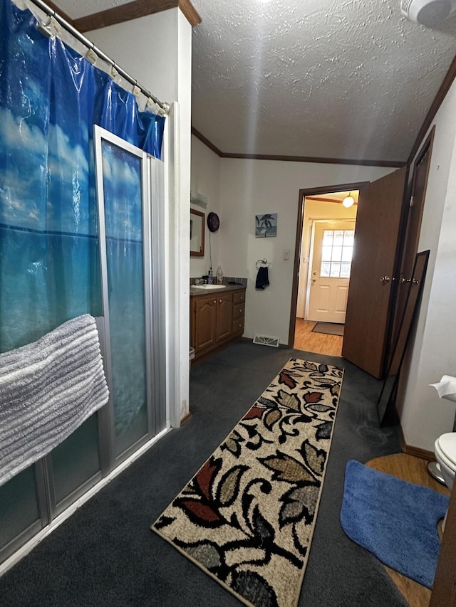 bathroom featuring a textured ceiling, ornamental molding, visible vents, a shower with shower curtain, and vanity