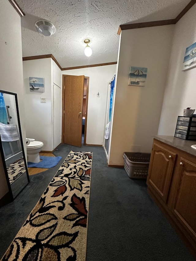 hall featuring dark carpet, ornamental molding, and a textured ceiling