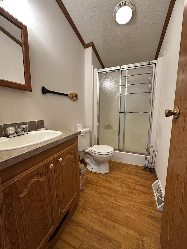 full bathroom with toilet, wood finished floors, a shower stall, vanity, and ornamental molding