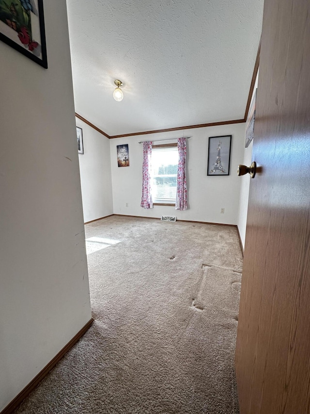 carpeted empty room with baseboards, ornamental molding, and a textured ceiling
