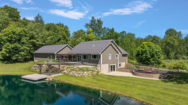 rear view of house with a patio, a garage, a yard, a deck with water view, and concrete driveway