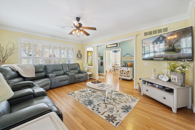 living area featuring crown molding, a ceiling fan, visible vents, and light wood-style flooring