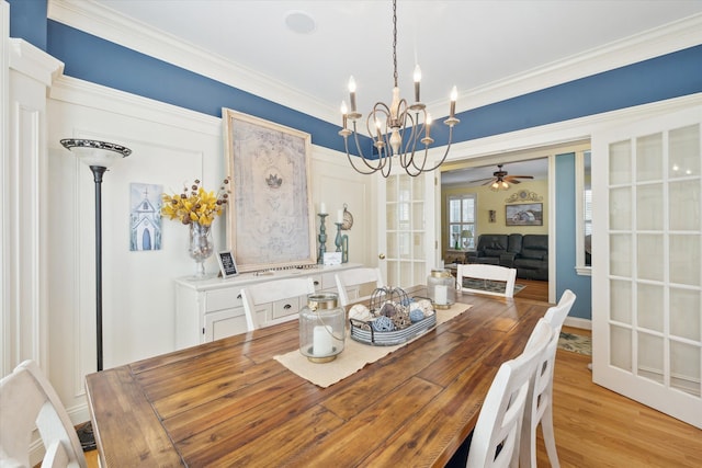 dining room with light wood-type flooring, ornamental molding, and ceiling fan with notable chandelier