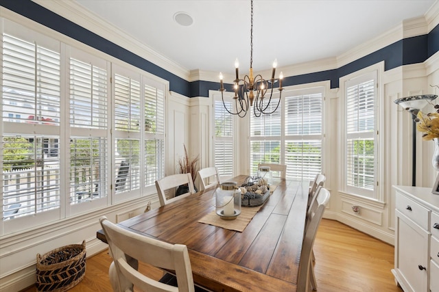 dining room with crown molding, light wood-style floors, a decorative wall, and a chandelier