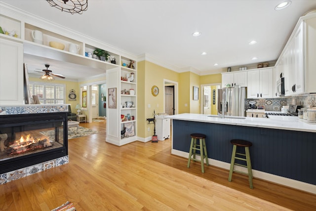 1728 Town Commons Dr, Howell, MI 48855 - kitchen featuring stainless steel appliances, a peninsula, open shelves, white cabinetry, and ornamental molding
