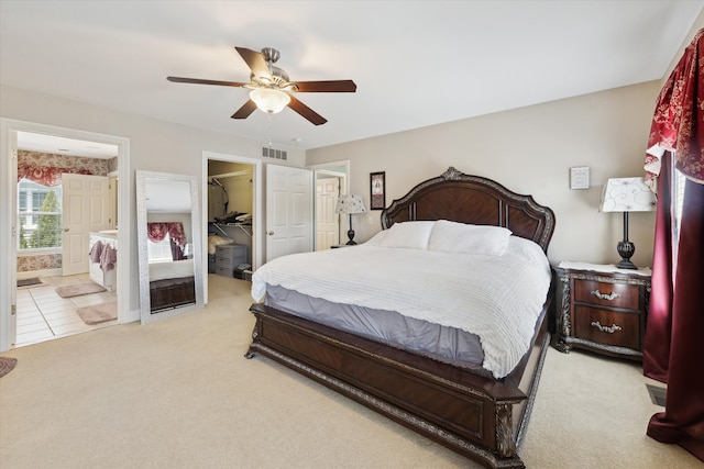 bedroom with light colored carpet, visible vents, a walk in closet, and ensuite bathroom