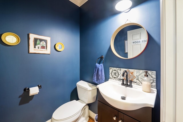 half bath with toilet, baseboards, and vanity