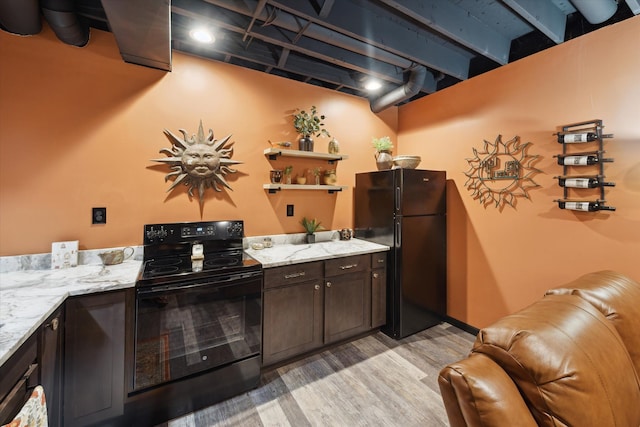 1728 Town Commons Dr, Howell, MI 48855 - kitchen with black appliances, light wood-style floors, dark brown cabinetry, and light stone countertops