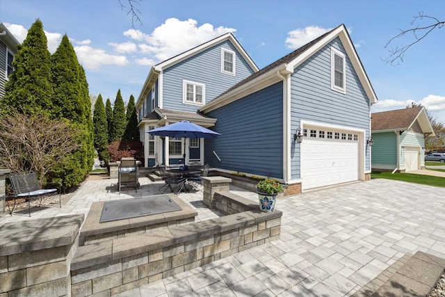 rear view of property featuring a patio and driveway