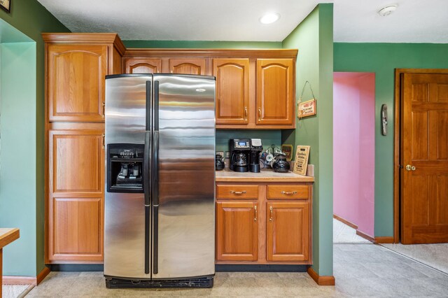 57480 72nd Ave, Hartford, MI 49057 - kitchen with stainless steel fridge with ice dispenser, brown cabinetry, light countertops, and baseboards