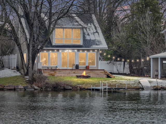 rear view of house with a water view, a fire pit, and fence