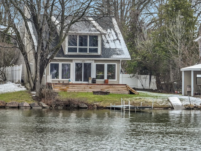 rear view of property featuring a water view and fence