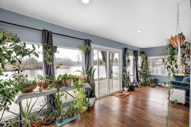 unfurnished sunroom featuring wood finished floors, recessed lighting, and a water view