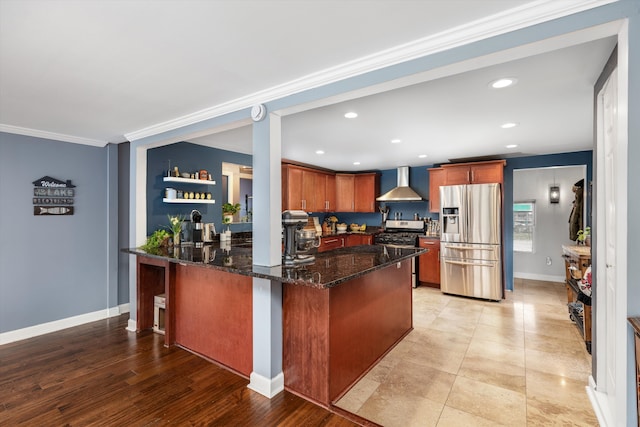 kitchen featuring recessed lighting, a peninsula, wall chimney exhaust hood, dark stone counters, and stainless steel appliances