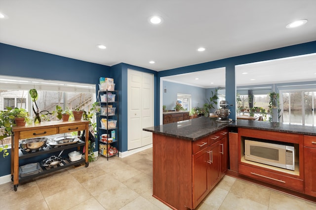kitchen with white microwave, recessed lighting, plenty of natural light, and dark stone counters