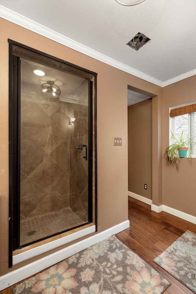 full bath with baseboards, crown molding, a stall shower, and wood finished floors